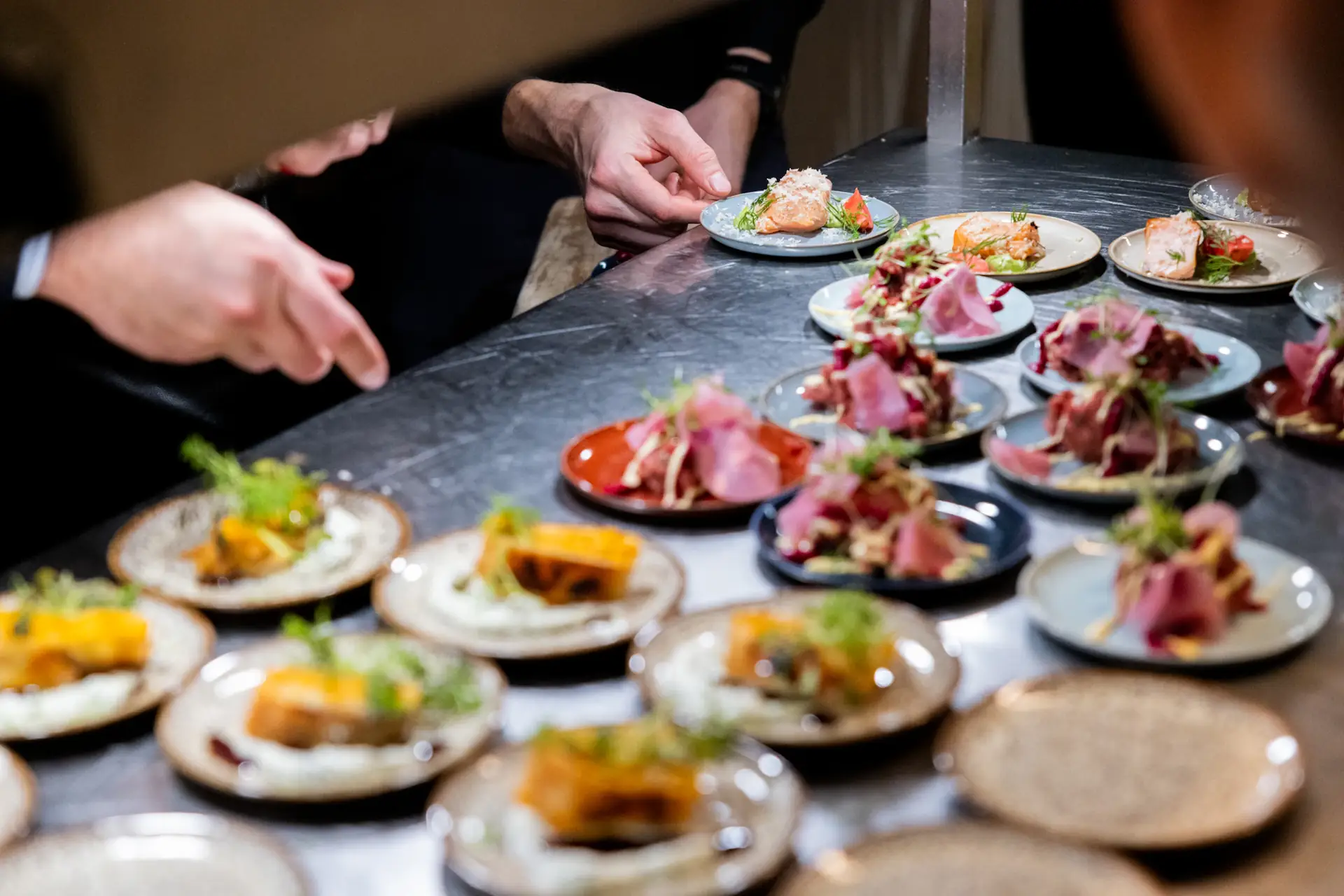 Chef finishing rows of small plated tasting courses