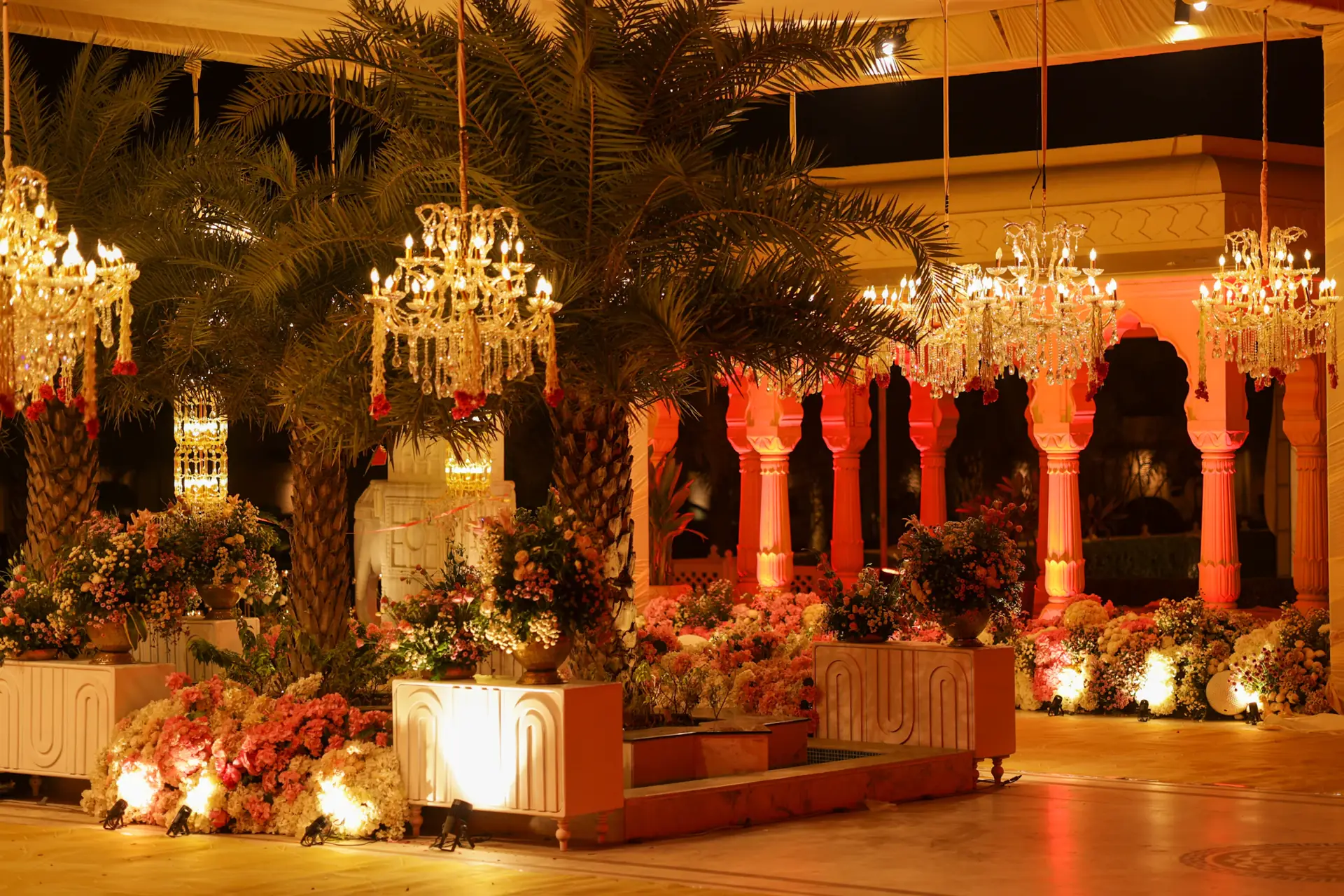 Red and gold celebration venue with chandeliers and floral arches